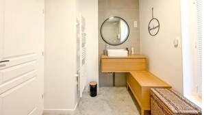 Casa de banho moderna com toucador branco, espelho redondo e tapete pequeno.