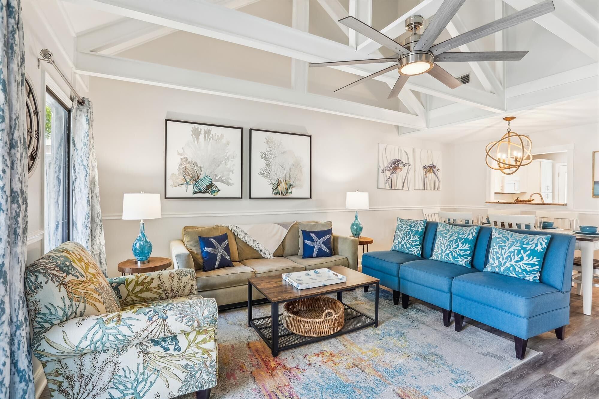 A spacious living room with a high ceiling, a ceiling fan, and a dining area in the background.