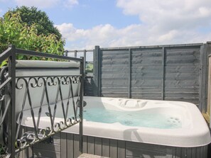 A hot tub with a metal railing, surrounded by a wooden fence and greenery. - Wayside Lodge (Craven Arms)