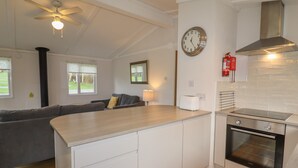 A modern kitchen with a built-in oven, a clock on the wall, and a ceiling fan.