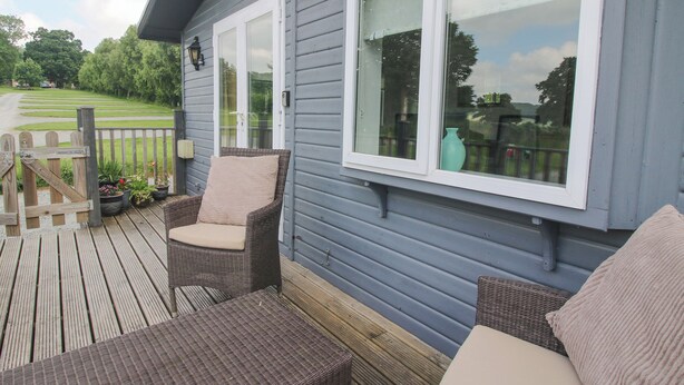 A wooden deck with wicker furniture and a view of a golf course.