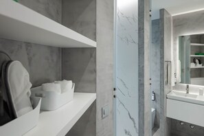 Ein modernes Badezimmer mit Marmor-Spritzschutz, einem weißen Waschbecken und einem Spiegel.