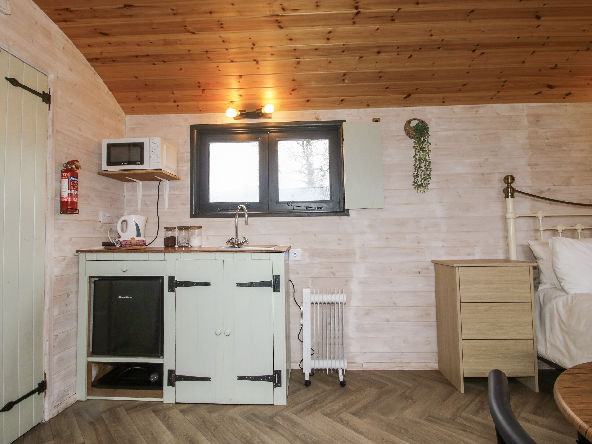 Una habitación pequeña con kitchenette, una cama y un radiador.
