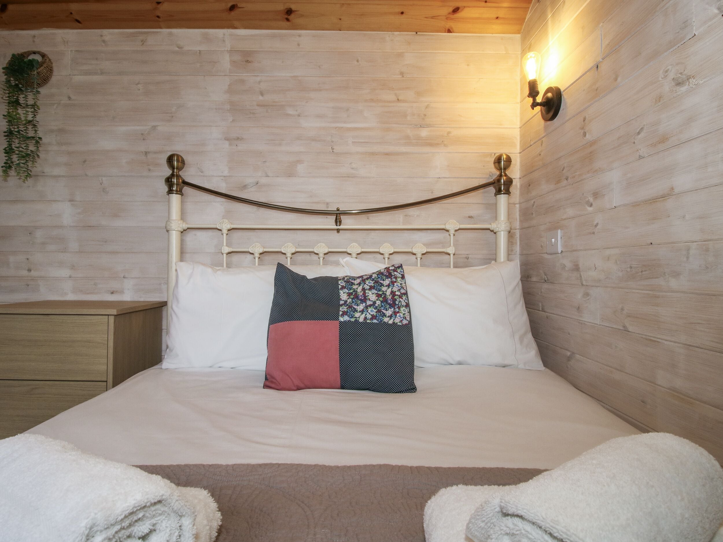 A bed with a metal headboard, white bedding, and a decorative pillow.