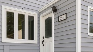 Une maison avec une porte d’entrée blanche, une boîte aux lettres et le numéro 211.