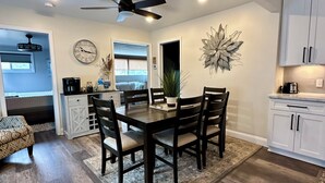 Un coin repas avec une table et des chaises en bois, un ventilateur de plafond et un élément décoratif mural.