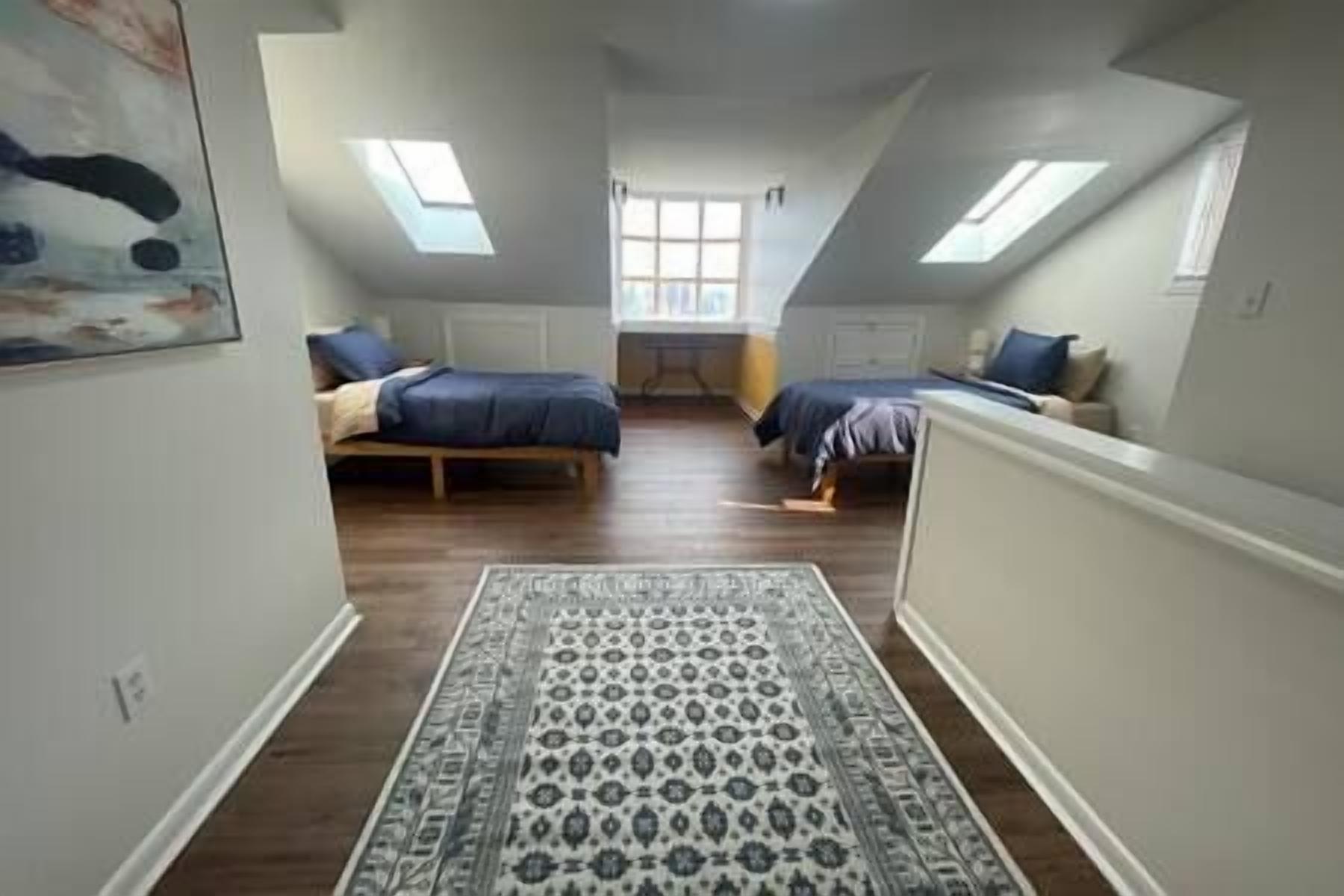 A room with two beds, a patterned rug, and skylights.