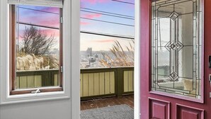 A door with a glass panel and a view of a cityscape through a window. - Fine View | Rooftop Deck | 4BR (Pittsburgh)