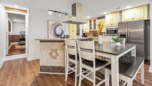 A modern kitchen with a central island, stainless steel appliances, and yellow cabinets. - Fine View | Rooftop Deck | 4BR (Pittsburgh)