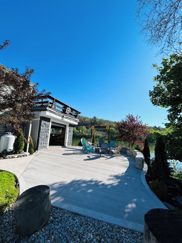 A patio with outdoor furniture, a stone wall, and a view of a lake.