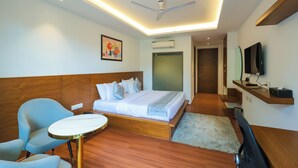 Una habitación de hotel moderna con una cama, un escritorio, una silla, un televisor y un ventilador de techo.