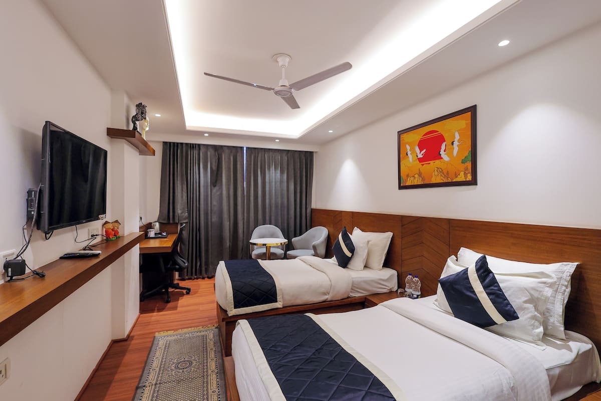 A hotel room with a bed, desk, chair, and a television.