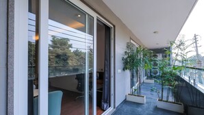 Un balcón moderno con puertas de cristal, una zona de estar y plantas en macetas.