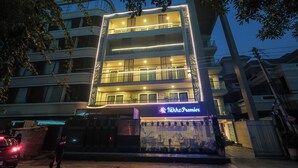Un hotel de varios pisos con balcones y una entrada bien iluminada.
