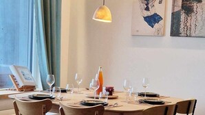 Een eetruimte met een ronde tafel, stoelen en hanglampen.