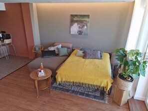Une chambre confortable avec un lit, une petite table sur laquelle se trouve une bouteille, une chaise et une plante.