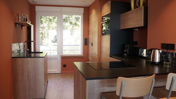 Een moderne keuken met een centraal eiland, een ingebouwde oven en een raam dat voor natuurlijk licht zorgt.
