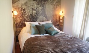 A bed with a patterned headboard, two bedside lamps, and a textured throw blanket.