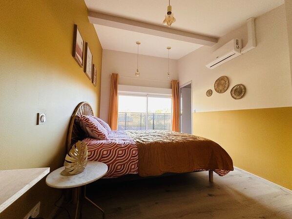 A bedroom with a bed, a small table, and a window with curtains. - Splendide Villa au Coeur de Sarlat, Entièrement Rénovée, Avec Piscine et Jacuzzi (Sarlat-la-Canéda)