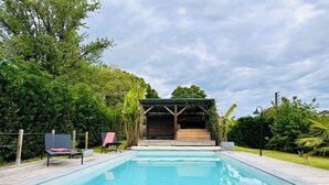 Una piscina rectangular con una terraza de madera alrededor.