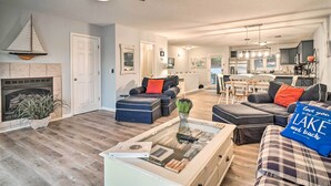 A spacious living room with a fireplace, a ceiling fan, and a dining area with a table and chairs. - Deerfield Lakefront Condo/Boat Slip Included! (LaFollette)