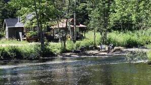 Una baita sul fiume con una terrazza e un piccolo pontile.