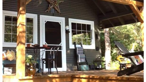 Un rustico chalet con una veranda in legno, due ampie finestre e una porta.