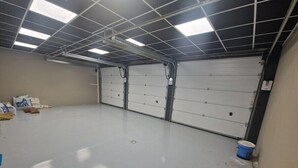 A clean, empty garage with a smooth floor, metal ceiling, and white garage doors. - La Baraque de l'Empereur (Boulogne-sur-Mer)