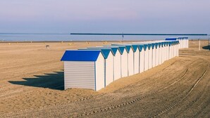 A row of beach huts with a sandy beach and a calm sea in the background. - La Baraque de l'Empereur (Boulogne-sur-Mer)