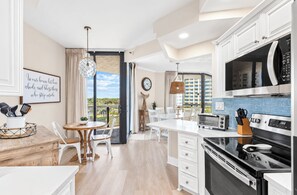 A modern kitchen with a dining area, a view of buildings, and a sign on the wall. - Gulf views+ Private beach! Restaurant on site! (Santa Rosa Beach)