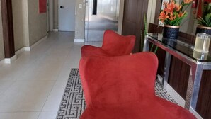 Ein modernes Interieur mit einem rot gepolsterten Sessel, einem Edelstahlkühlschrank und einer Bartheke mit Glasplatte und Blumentöpfen.
