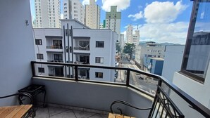 Ein Balkon mit Blick auf hohe Gebäude, einem Fliesenboden und einem Metallgeländer.