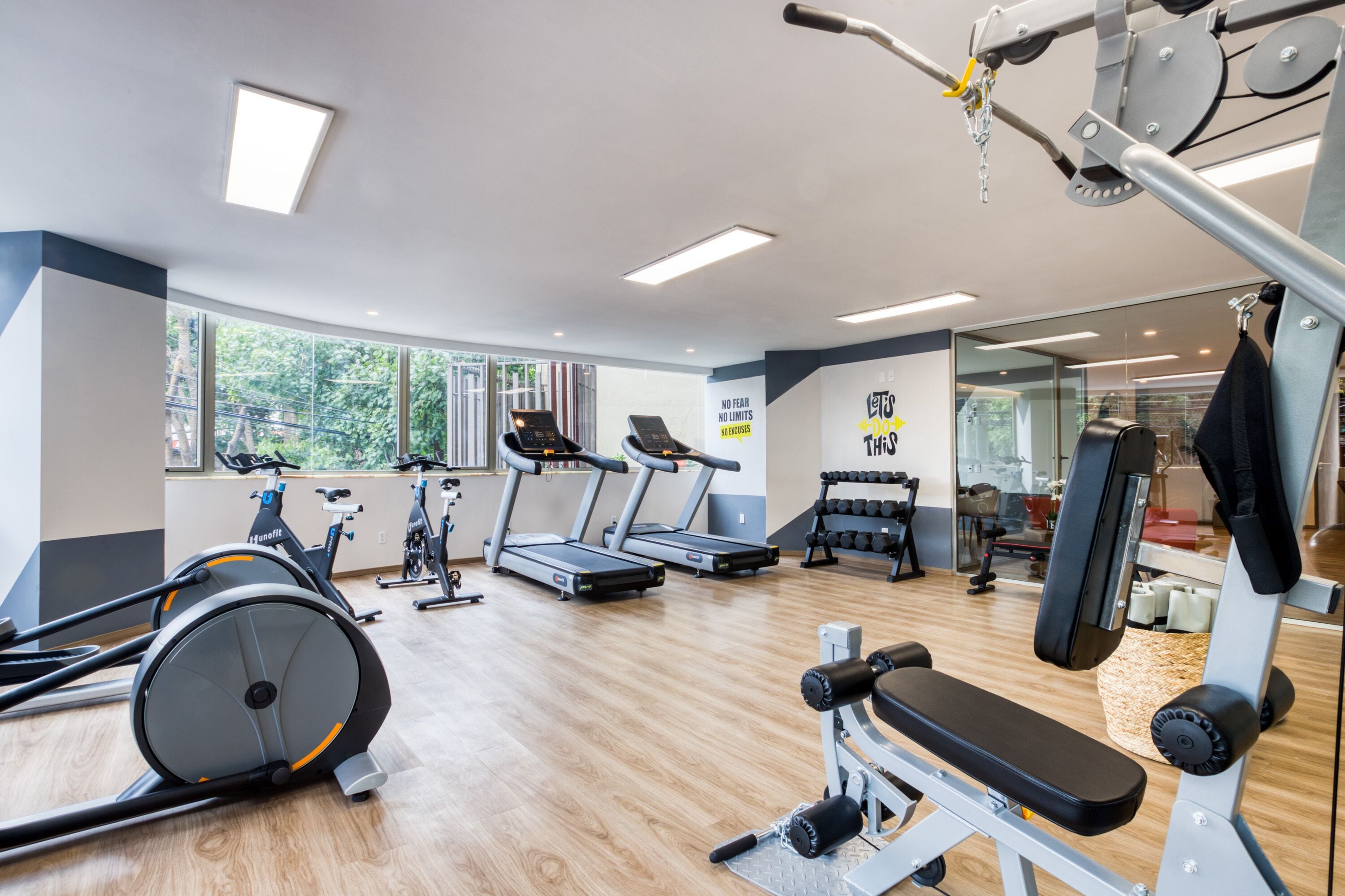 Een fitnessruimte met loopbanden, hometrainers en krachtapparaten.