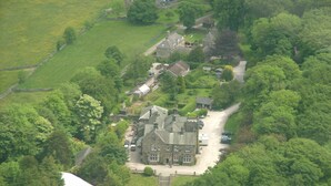 An aerial view of a large estate with multiple buildings, including a prominent house with a large driveway and several parked cars. - Cosy self catering apartment in large Victorian Residence (Buxton)