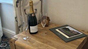 Een houten tafel met champagne, twee glazen en een lijst met een foto.
