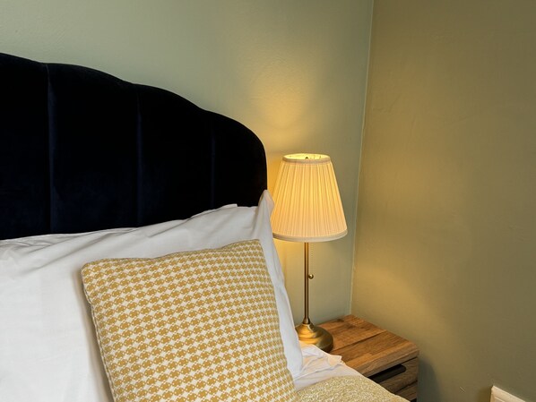 A bed with a dark headboard, a bedside lamp, and patterned pillows.