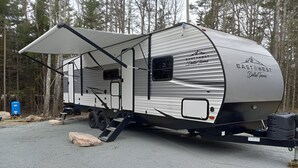 Suuri matkailuauto, jossa on katettu oleskelutila, keittiö ja makuutila.