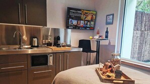 A modern kitchen with a built-in oven, a coffee maker, and a TV mounted on the wall displaying a program.