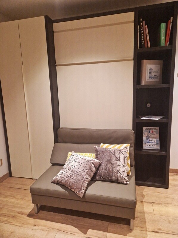 Una sala de estar moderna con sofá, cojines, una estantería y un armario.