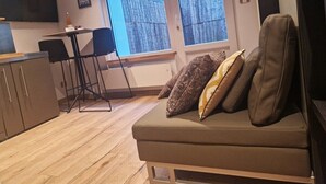 A modern living room with a sofa, a dining table, and a TV.