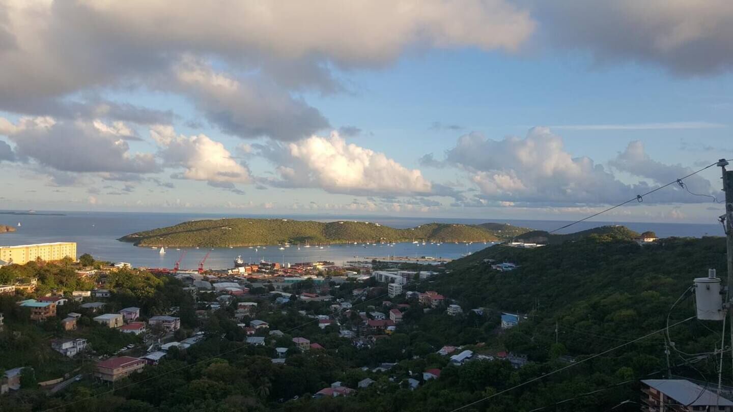 A coastal town with a view of the sea, hills, and a distant island.
