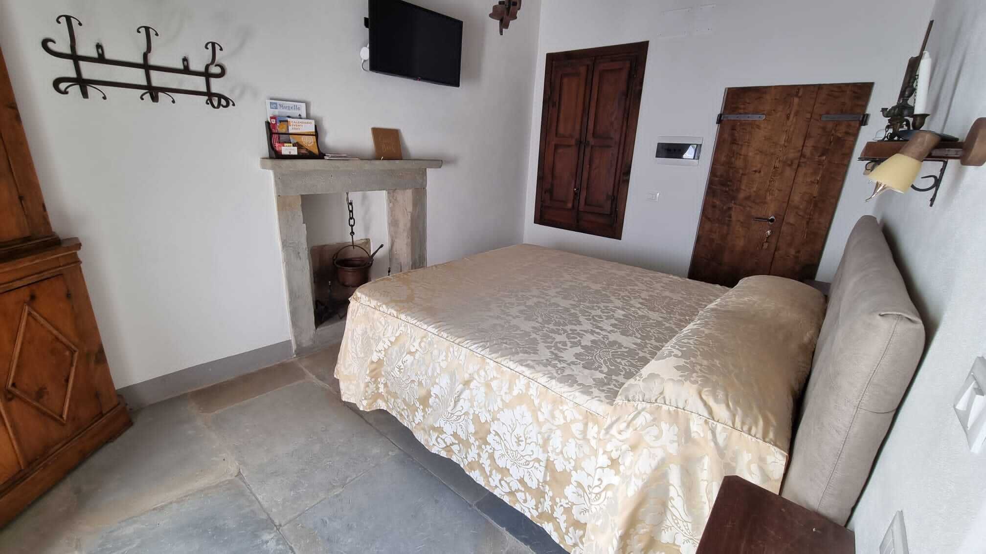 Ein Schlafzimmer mit einem Bett, einem Holzschrank, einem kleinen Tisch mit Lampe und einem an der Wand befestigten Fernseher.