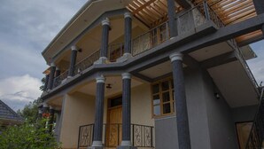 A multi-story house with a balcony, columns, and a stone foundation. - Mt. Rwenzori Golf Resort & Spa (Fort Portal)