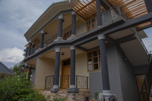 Una casa de varios pisos con balcón, columnas y base de piedra.