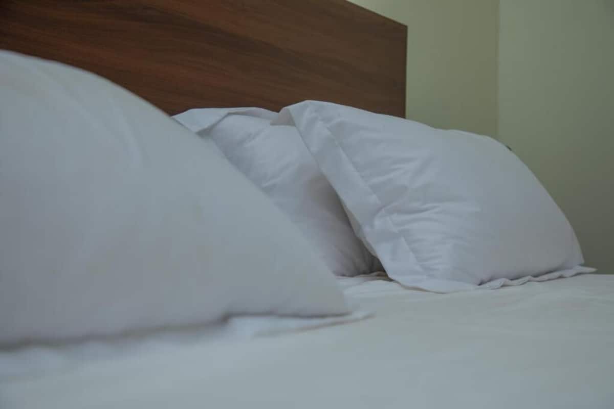 A bed with white bedding and a wooden headboard.