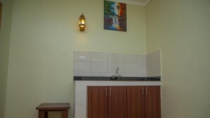 A kitchen with a wooden cabinet, a small table, and a tiled backsplash. - Mt. Rwenzori Golf Resort & Spa (Fort Portal)