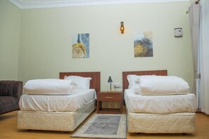 A hotel room with two beds, a nightstand, a lamp, and artwork on the wall. - Mt. Rwenzori Golf Resort & Spa (Fort Portal)