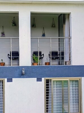 Edifício com varanda decorada com vasos de plantas e móveis para área externa.