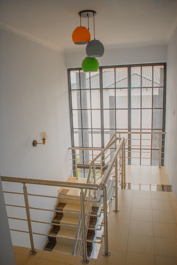 A staircase with metal railings and a view of a building outside through large windows.
