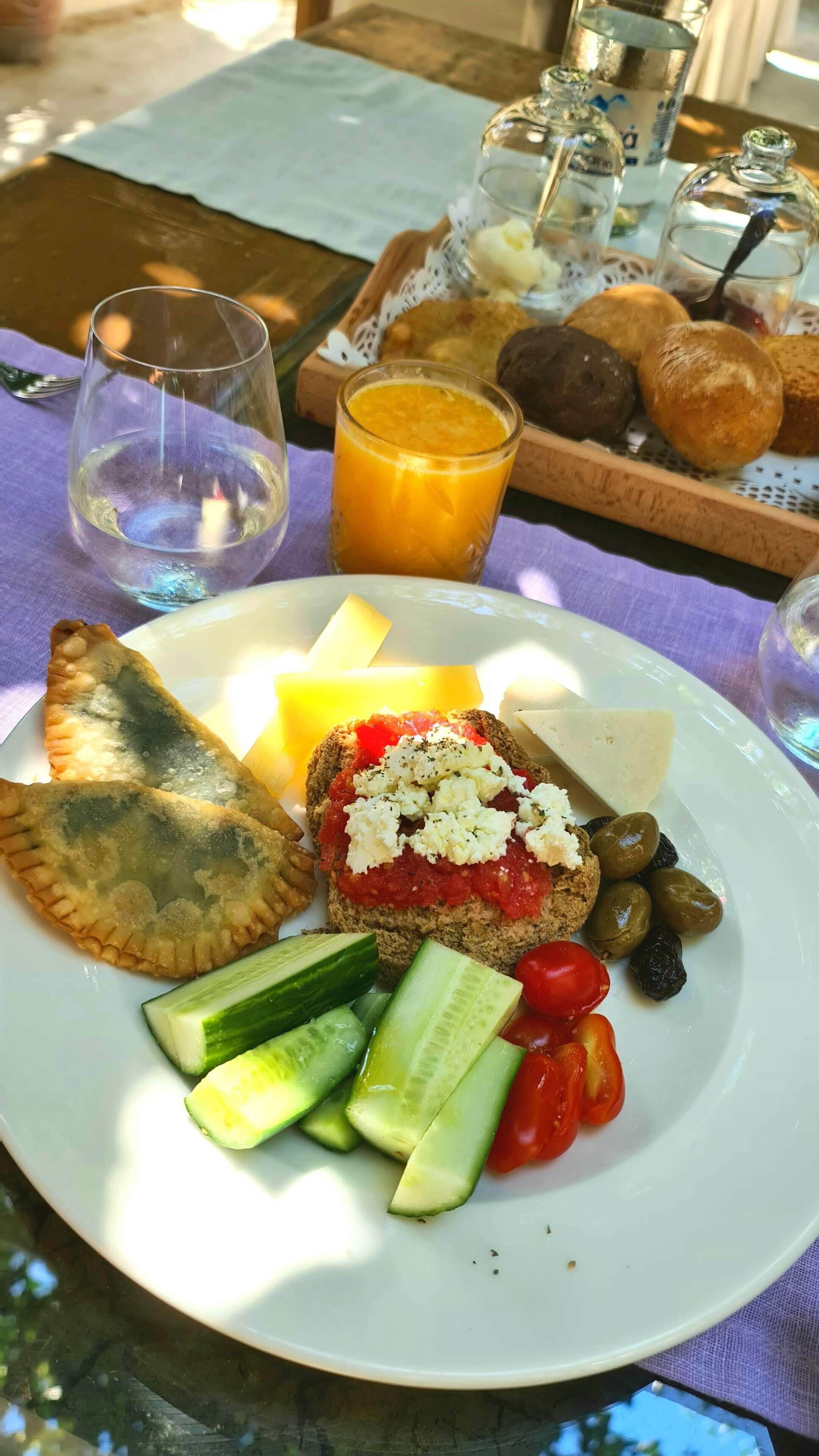 Un plat amb aliments: una llesca de pa amb tomàquet i formatge, un pastís, rodanxes de pepino, tomàquets cherry i olives.
